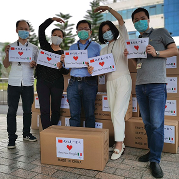 Five people in front of boxes holding signs with hearts