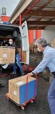 Three people loading boxes of masks onto a truck